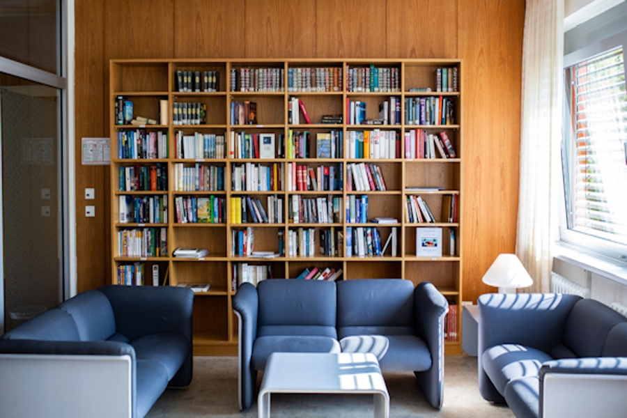 Bibliothek mit vielen Bücher in Regalen und einer Sitzgarnitur
